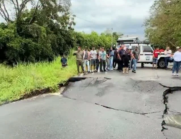 Personas y vehículos detenidos frente al tramo de carretera colapsado