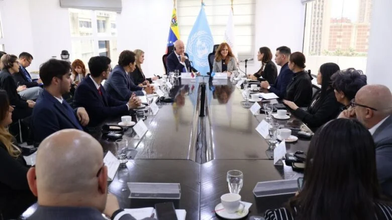 Delegaciones de la Defensoría del Pueblo y de ACNUR reunidas en una mesa larga, con las banderas de Venezuela y de la ONU al fondo