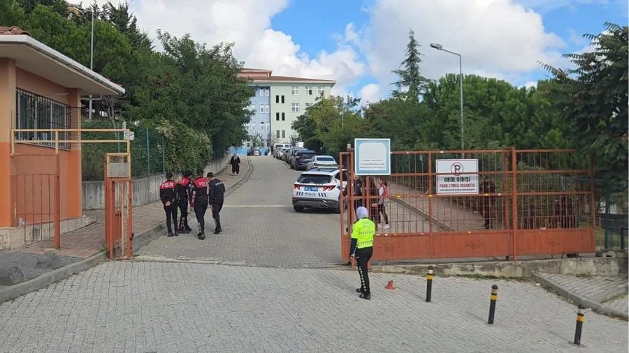 Policías caminan hacia la entrada de una escuela de Estambul, con una patrulla estacionada y una agente vigilando el portón