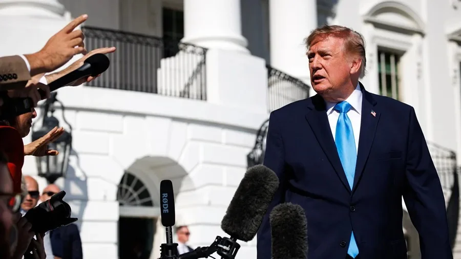 Donald Trump habla con periodistas frente a la Casa Blanca, rodeado de micrófonos