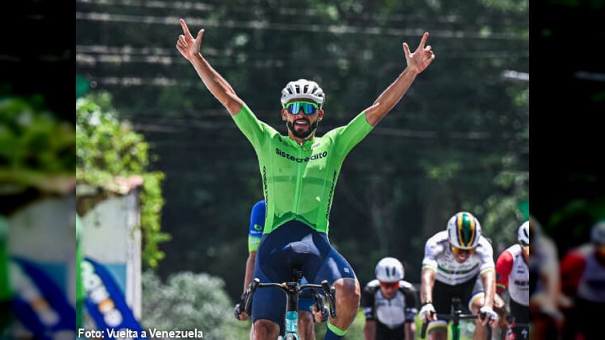Juan Diego Hoyos, con el maillot verde de Sistecrédito, celebra con los brazos en alto sobre la bicicleta, con otros ciclistas detrás