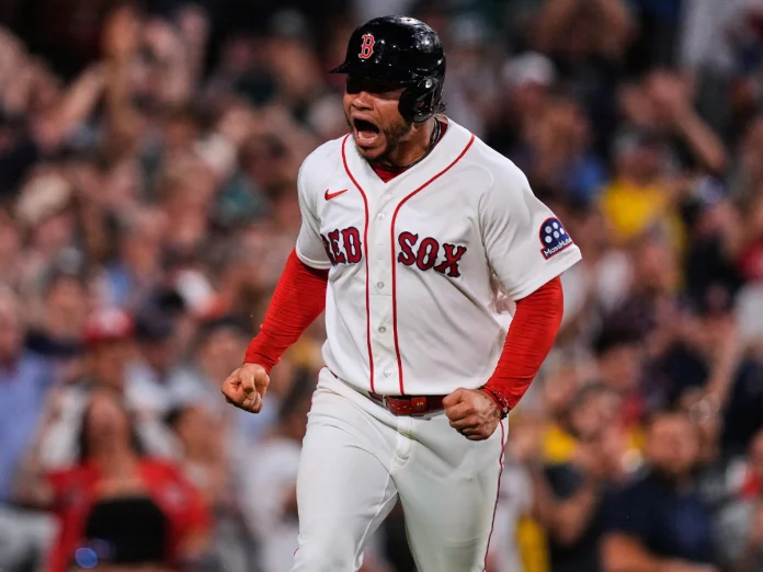 Willson Contreras grita y aprieta los puños con el uniforme y el casco de los Medias Rojas de Boston, con el público de fondo