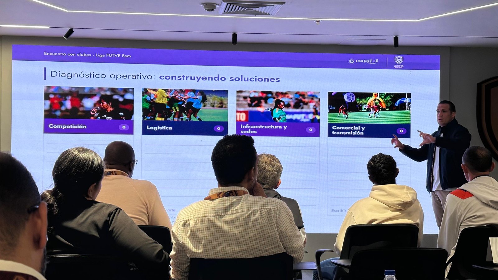 Un hombre expone ante una pantalla con el título «Diagnóstico operativo: construyendo soluciones» frente a representantes de clubes sentados en una sala