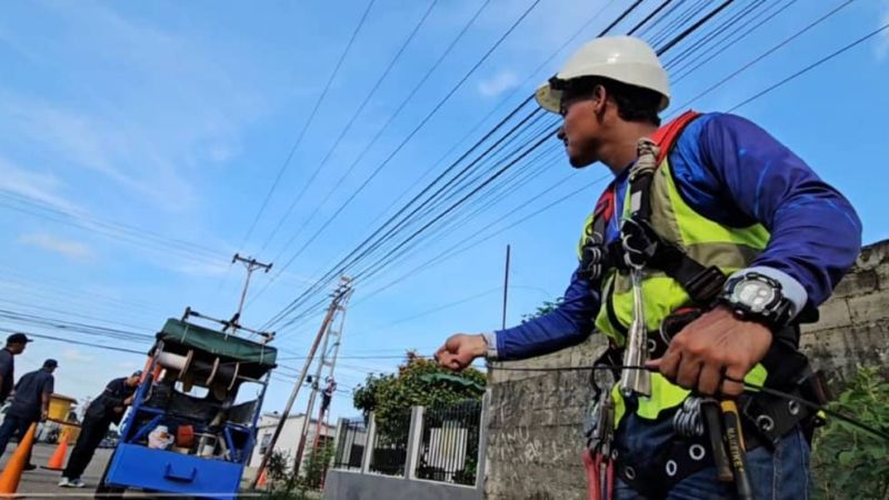 Un técnico de CANTV con arnés y casco revisa el cableado en un poste de una calle de Barinas