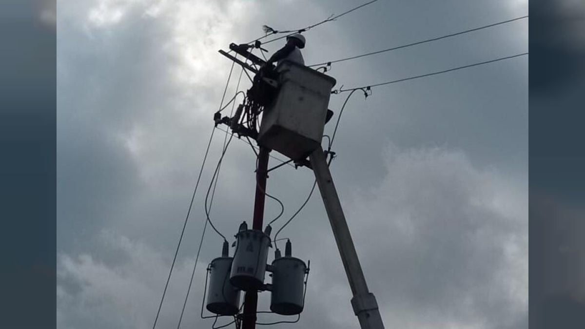Un trabajador de Corpoelec repara un poste con transformadores desde una cesta elevada