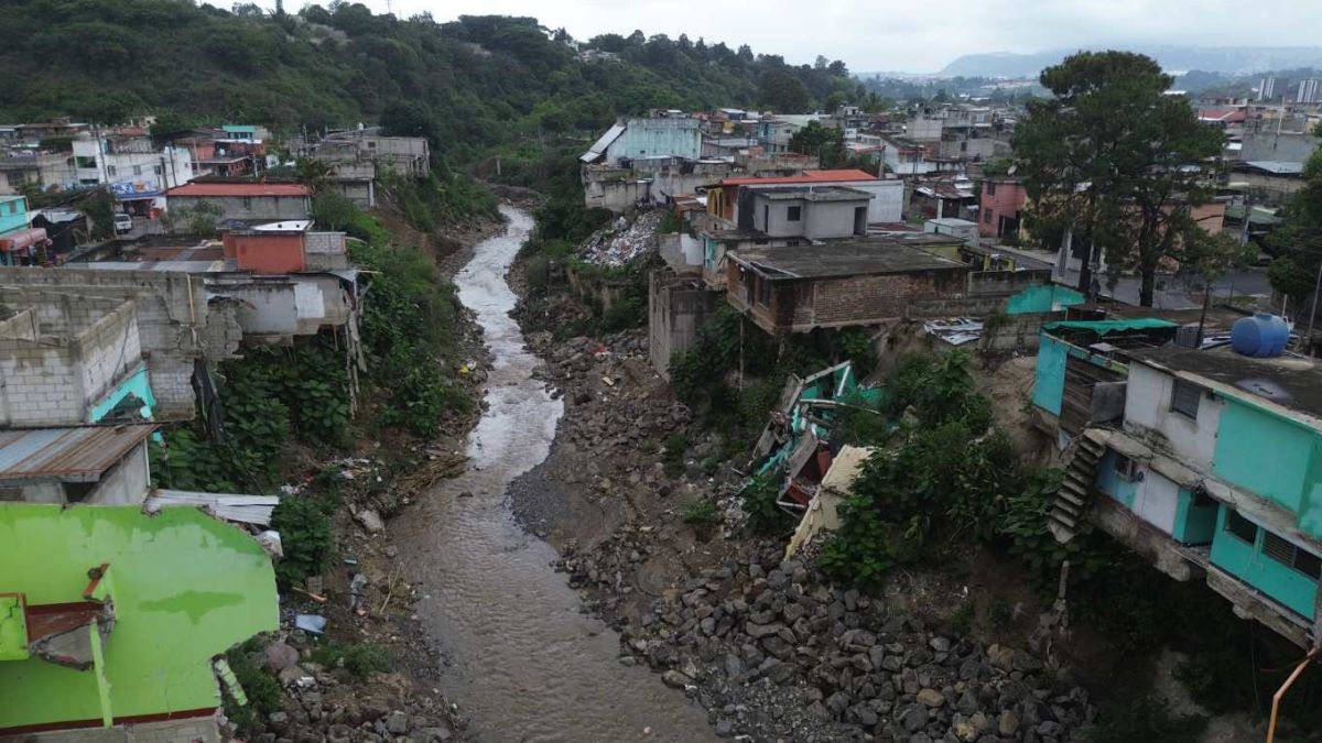 Vista aérea de un río crecido con viviendas dañadas en sus orillas, en Guatemala