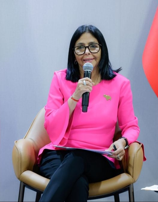 Delcy Rodríguez, sentada, habla con un micrófono