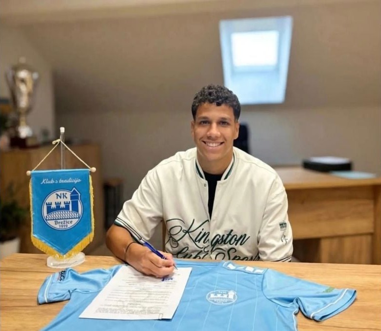 Jenluis Pérez firma su contrato junto a la camiseta y el banderín del NK Brežice 1919