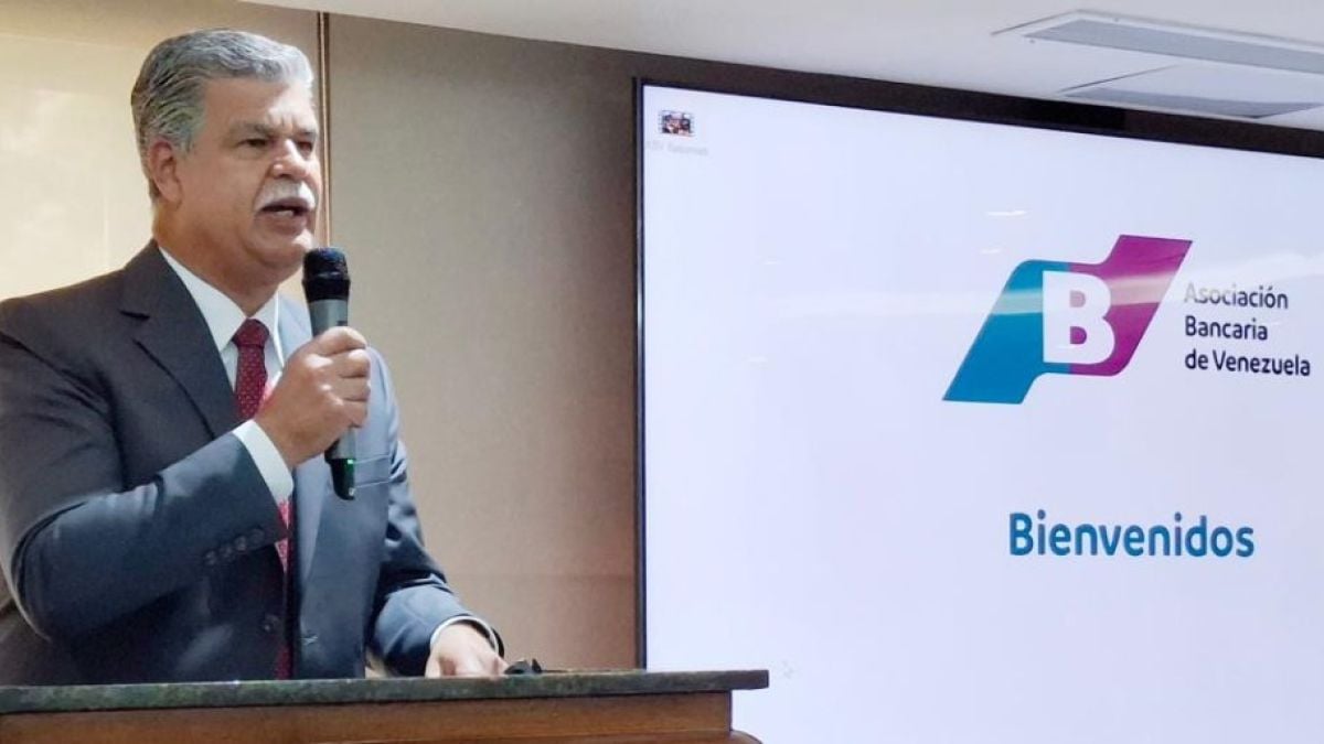 Pedro Pacheco habla con un micrófono junto a una pantalla con el logo de la Asociación Bancaria de Venezuela