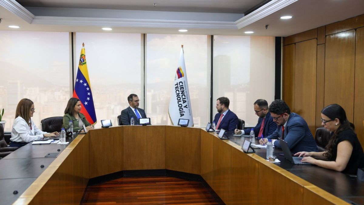 Funcionarios reunidos alrededor de una mesa con banderas de Venezuela y del Ministerio de Ciencia y Tecnología