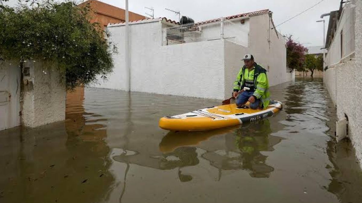 Un rescatista avanza sobre una tabla por una calle inundada