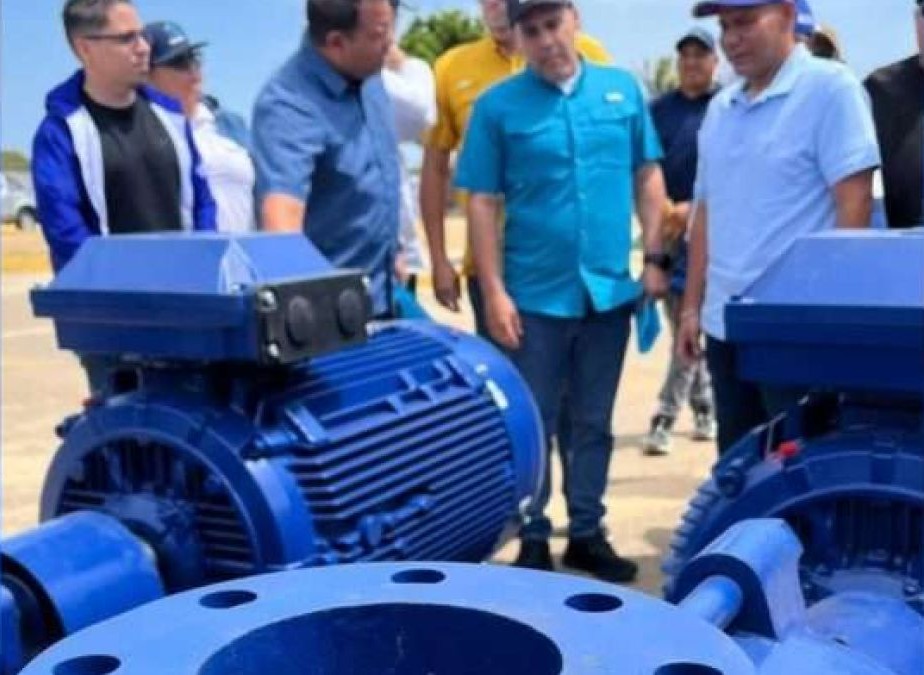 Funcionarios observan motores de bombeo nuevos, pintados de azul