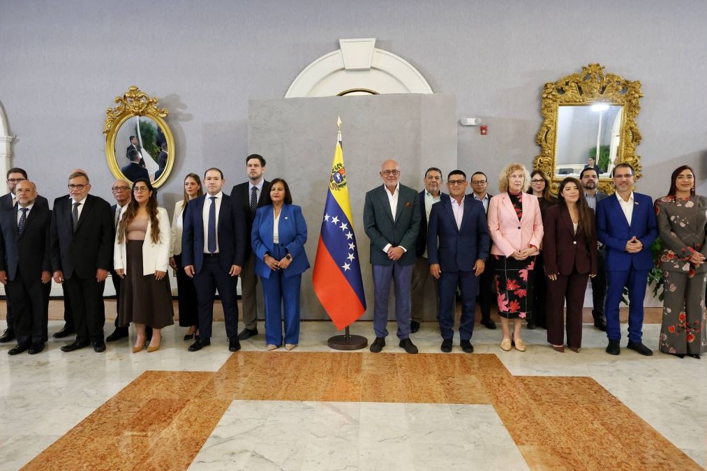 Las delegaciones del Gobierno y de la AN de 2015 posan junto a una bandera de Venezuela
