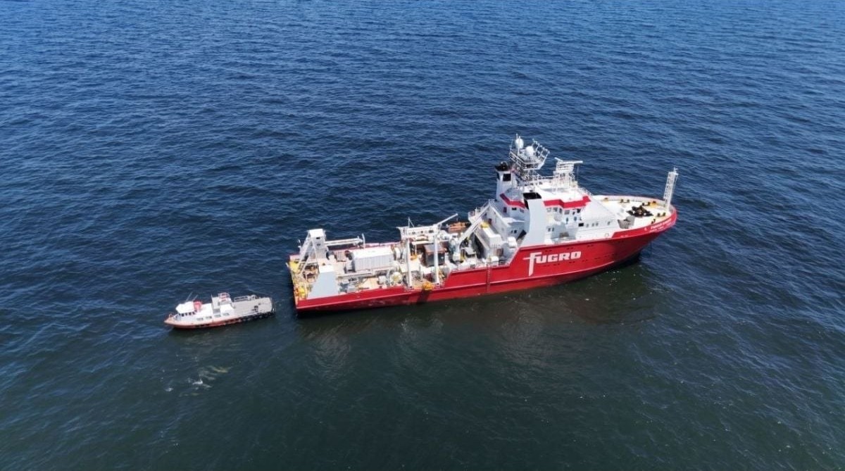 Un buque rojo de Fugro navega en mar abierto junto a una lancha