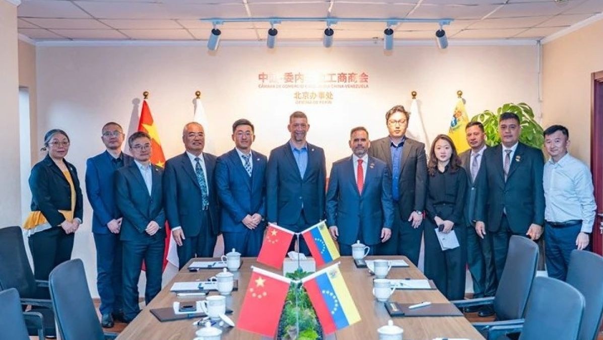 Un grupo de personas posa en la oficina de la cámara, con banderas de China y Venezuela sobre la mesa