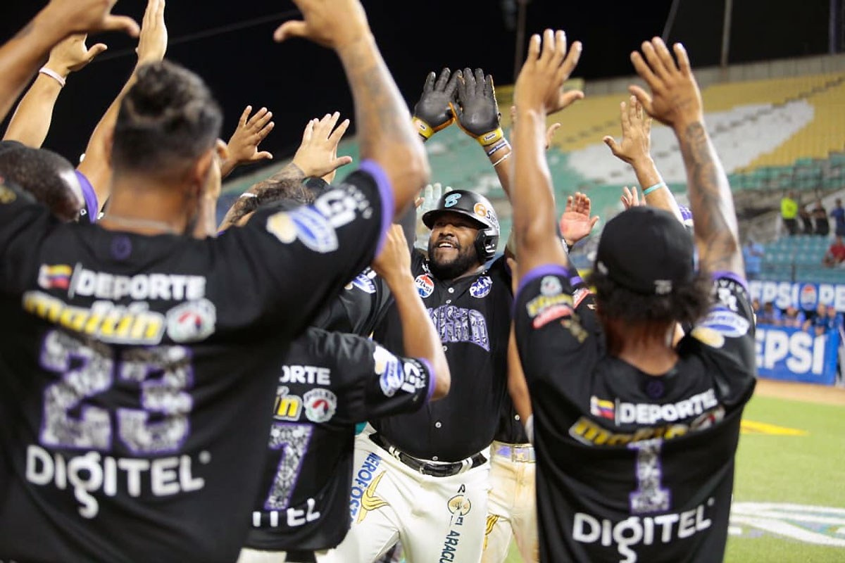Un jugador de Bravos de Margarita, con casco, es recibido por sus compañeros con los brazos en alto