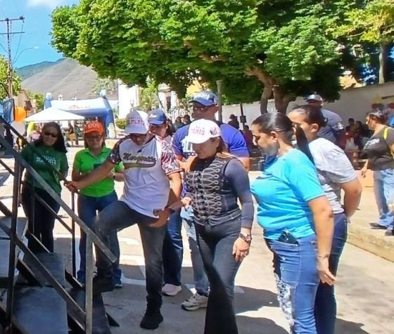 Personas hacen fila junto a la escalera de un camión en una feria al aire libre