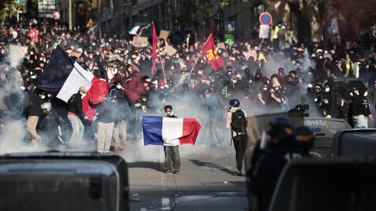 Manifestantes con banderas en una calle cubierta de gas