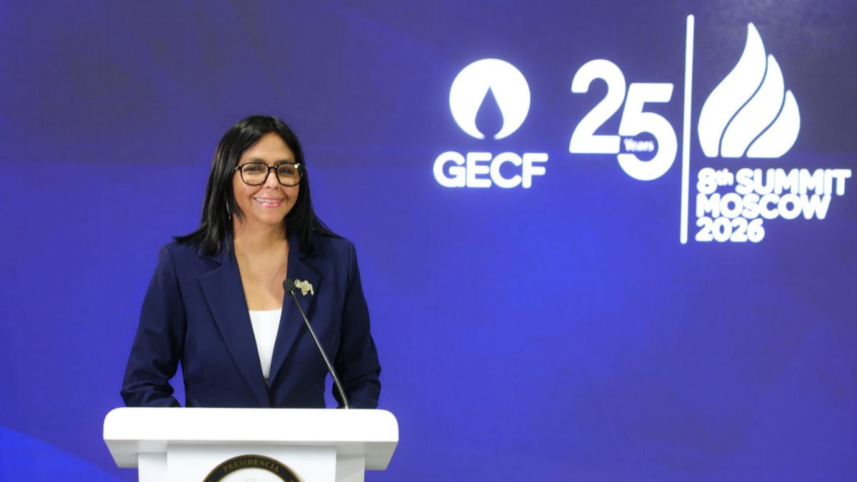 Una mujer sonríe tras un atril, frente a una pantalla con el logo de un foro internacional