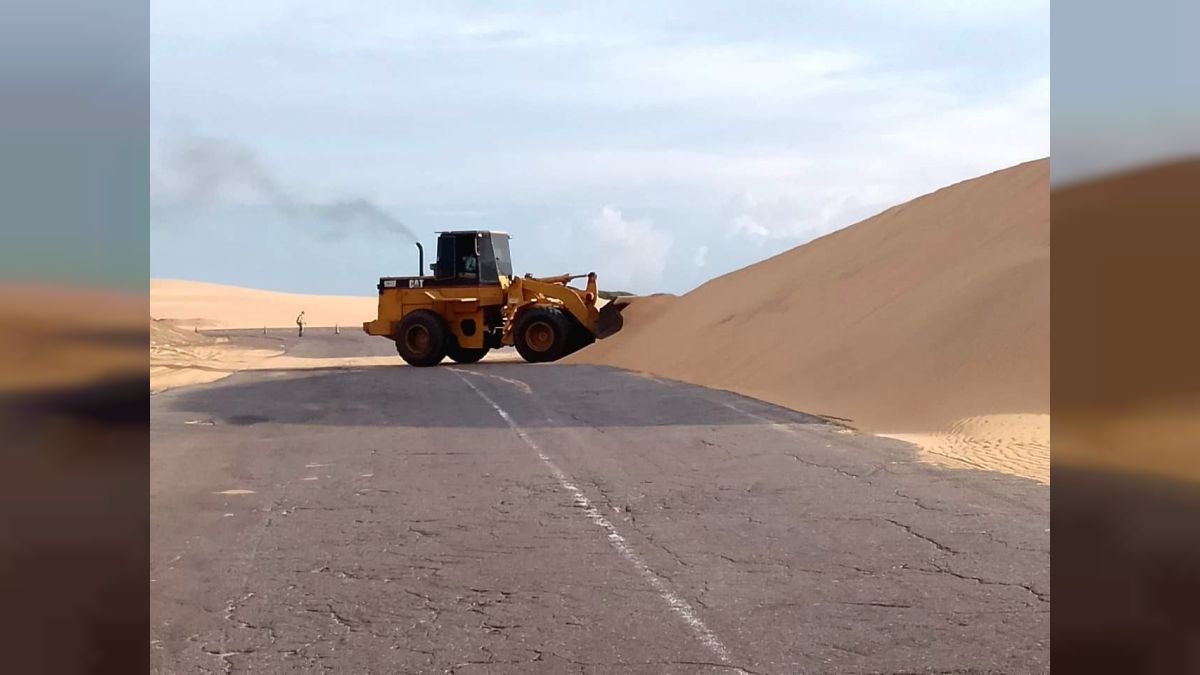 Un cargador frontal retira arena acumulada sobre una carretera