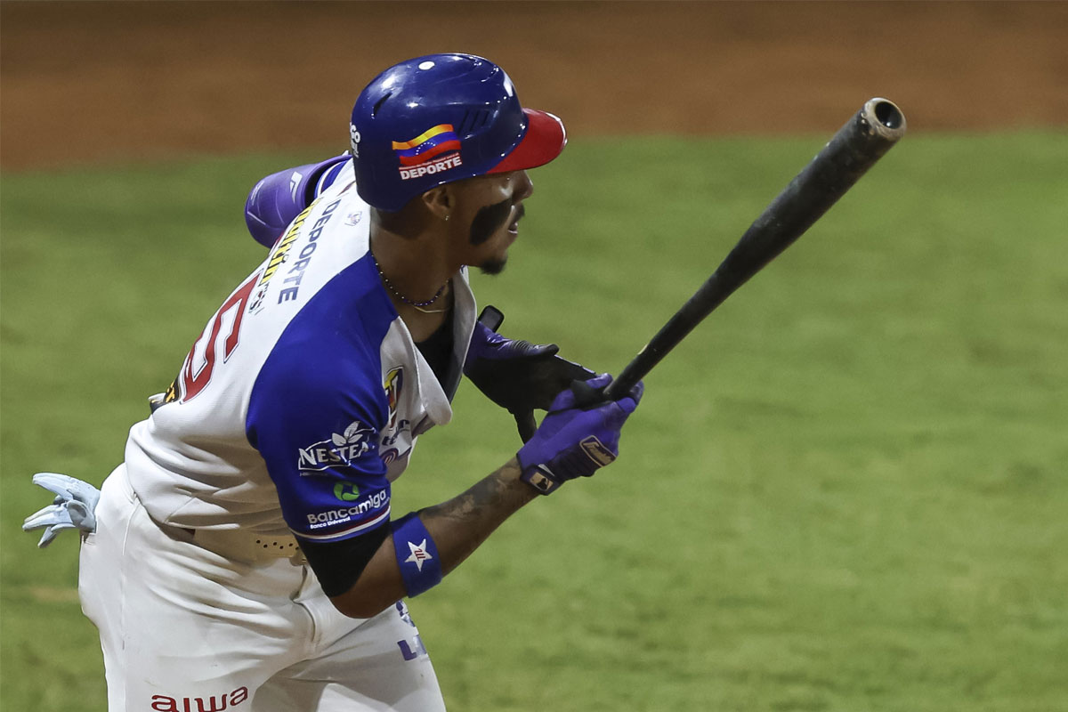 Un bateador con casco azul y uniforme blanco y azul tras hacer un swing